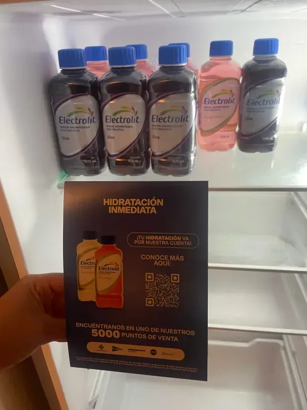 Nevera de alojamiento con botellas de Electrolit y una tarjeta con código QR