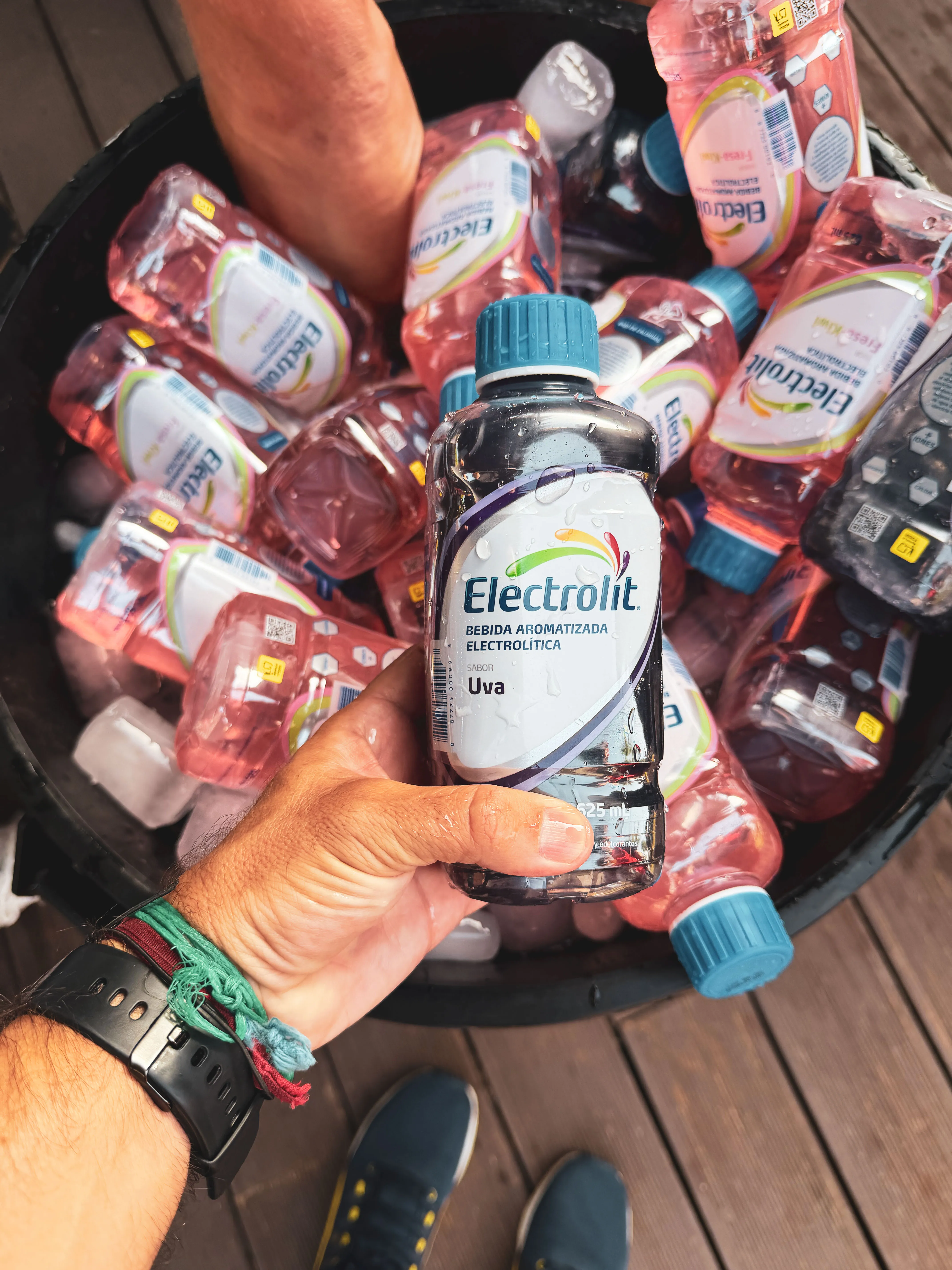 Botellas de Electrolit sabor uva enfriándose dentro de un cubo lleno de hielo
