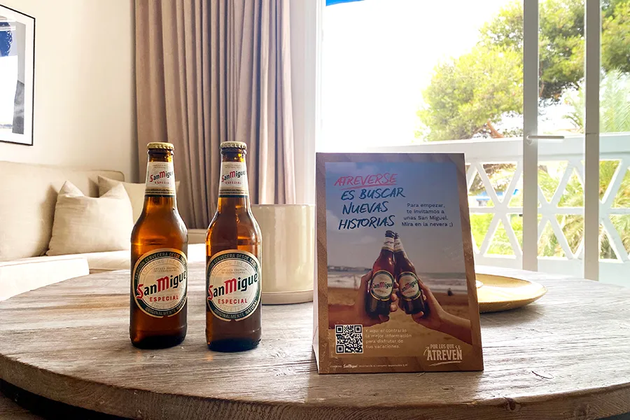 Botellas de San Miguel y un flyer de la promoción sobre una mesa de la habitación