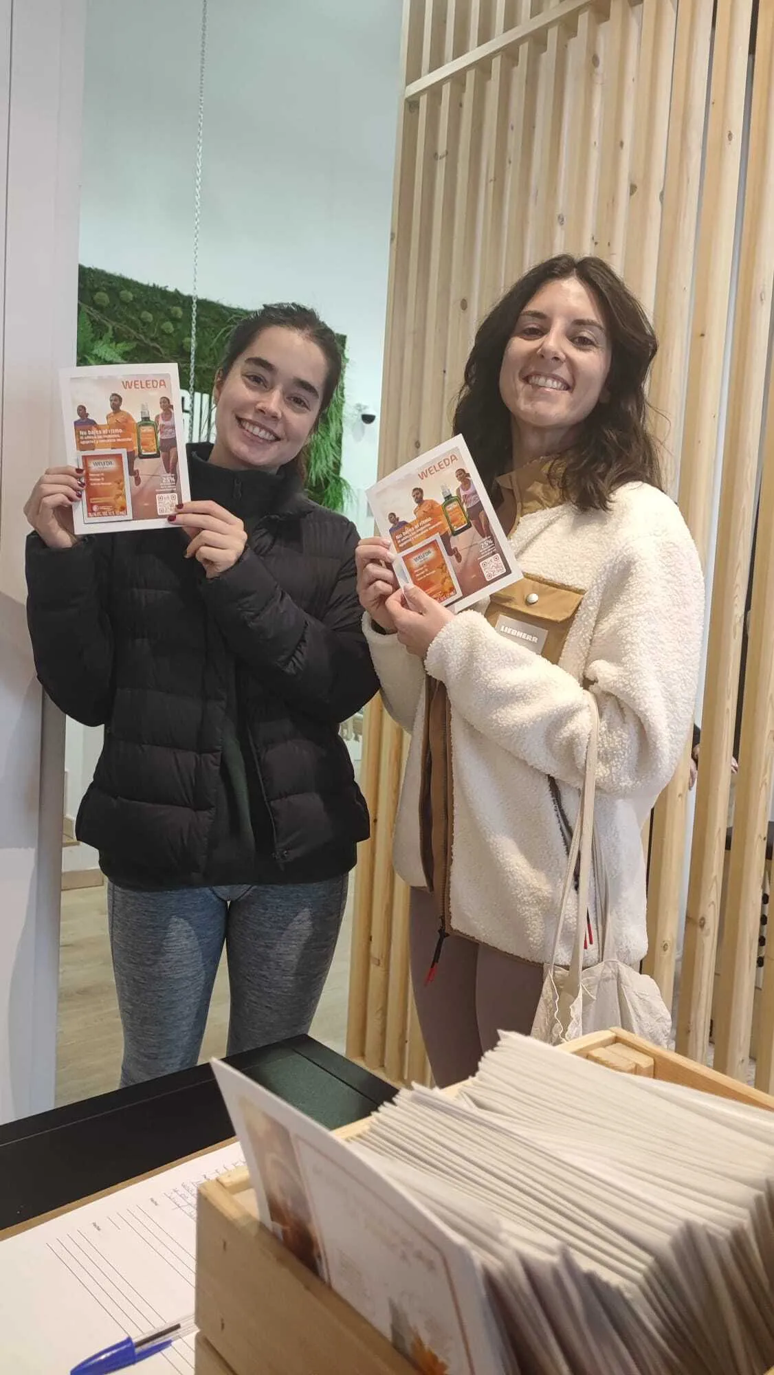Dos promotoras con flyers de Weleda Árnica en el interior de una tienda
